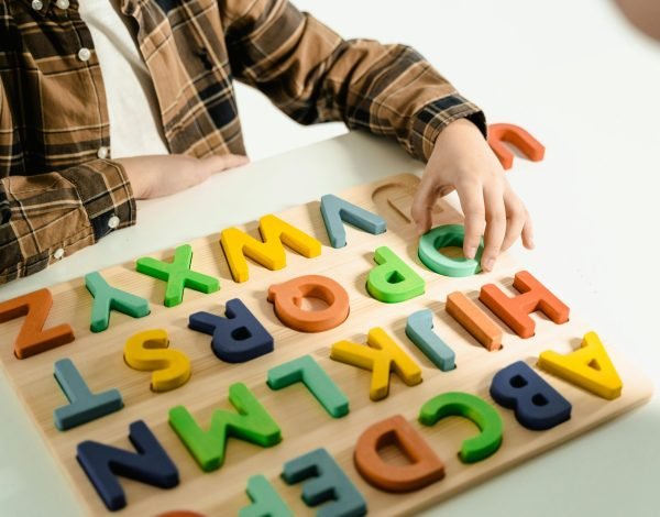 A child interacts with bright wooden alphabet letters, engaging in educational play.